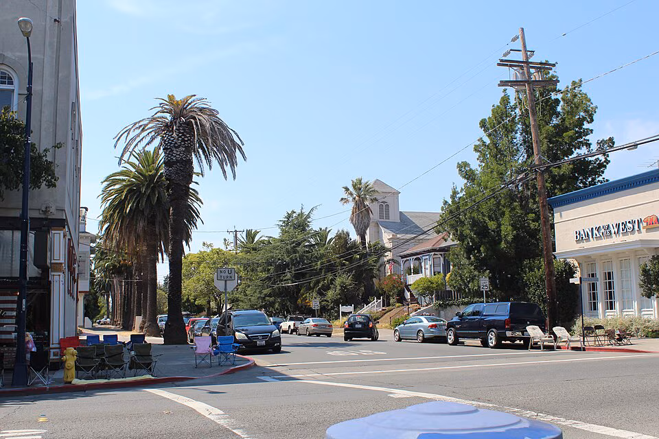 Palm-lined street corner in downtown Benicia with parked cars and historic buildings